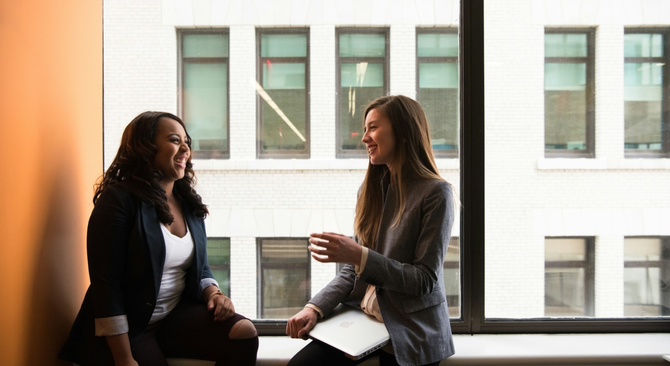 Two colleagues sitting together having a friendly conversation.