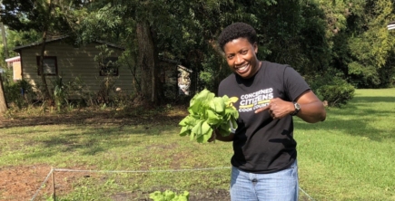 Dr. Treva Gear, founder of Concerned Citizens of Cook County (4C) holding up a head of lettuce in a community garden.