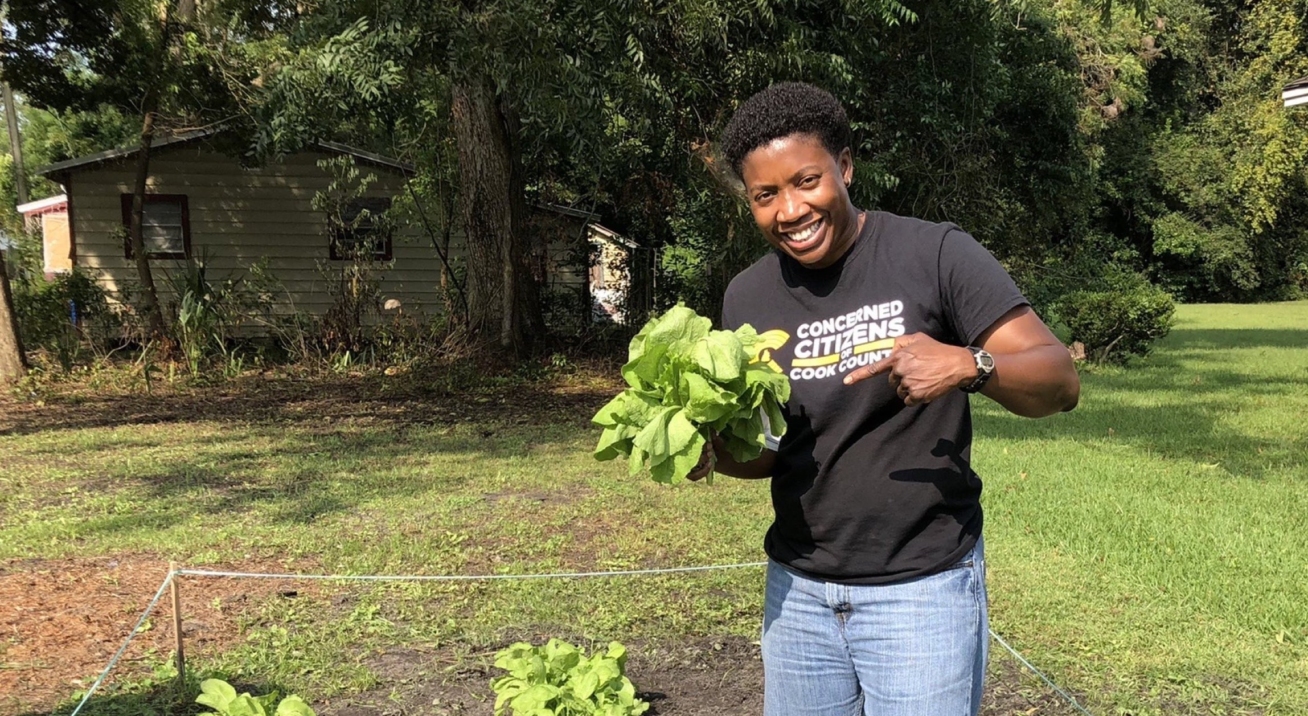 Dr. Treva Gear, founder of Concerned Citizens of Cook County (4C) holding up a head of lettuce in a community garden.