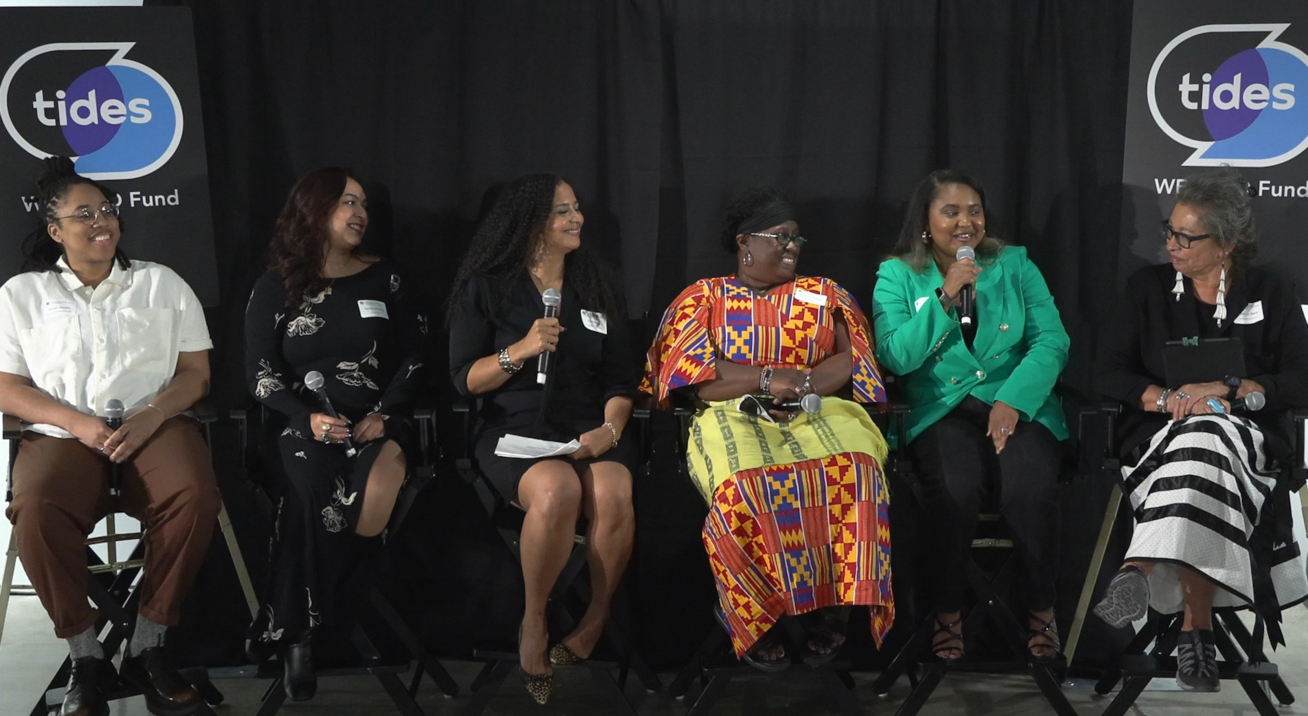 A group of 6 women sitting on tall stools, speaking at a panel discussion